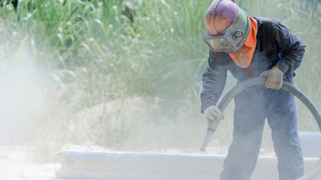 A worker Sand blasting outside